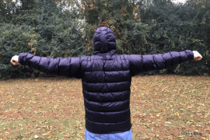 A man stands with his back facing the camera displaying the back of his black custom down Goosefeet Anorak jacket