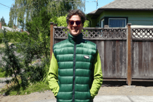 A happy customer wears a custom, full zippered forest green ultralight Goosefeet Gear down vest. (Zipped)